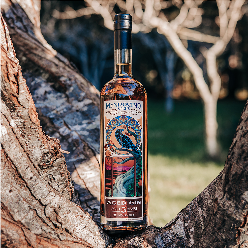Bottle of Mendocino Aged Gin in a natural setting with tree branches.
