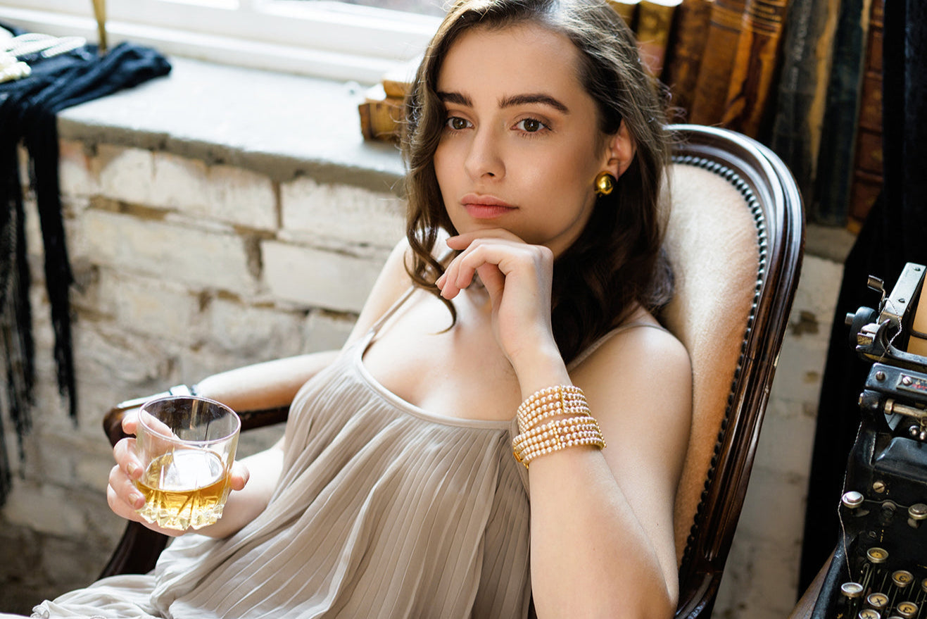 Woman sitting in a chair holding a glass of whiskey.